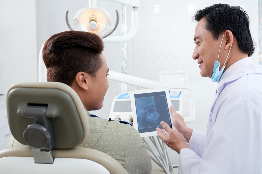 Asian male dentist demonstrating jaw x ray image tablet patient 1098 20365